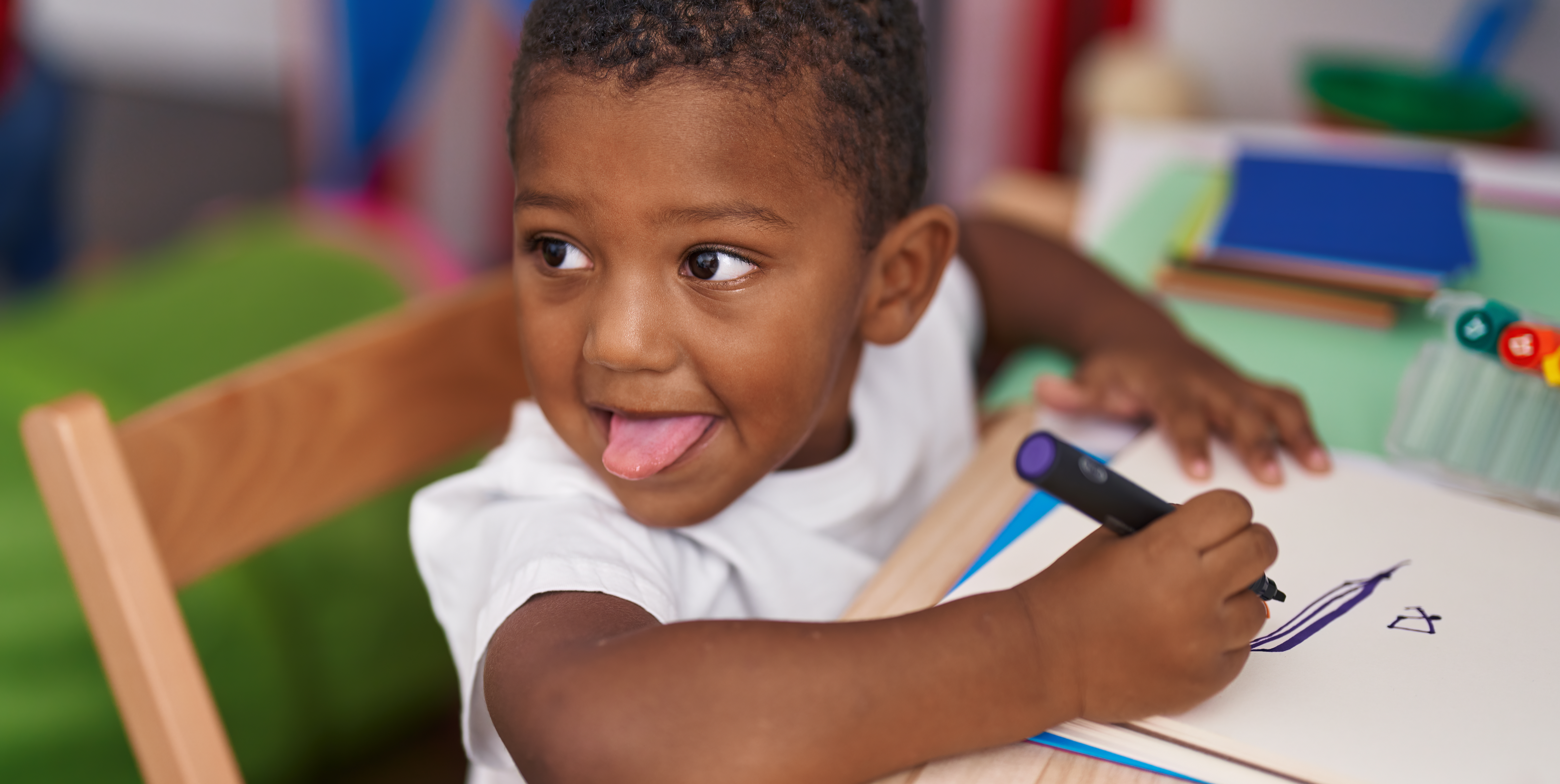 A child practising early writing at a wooden desk